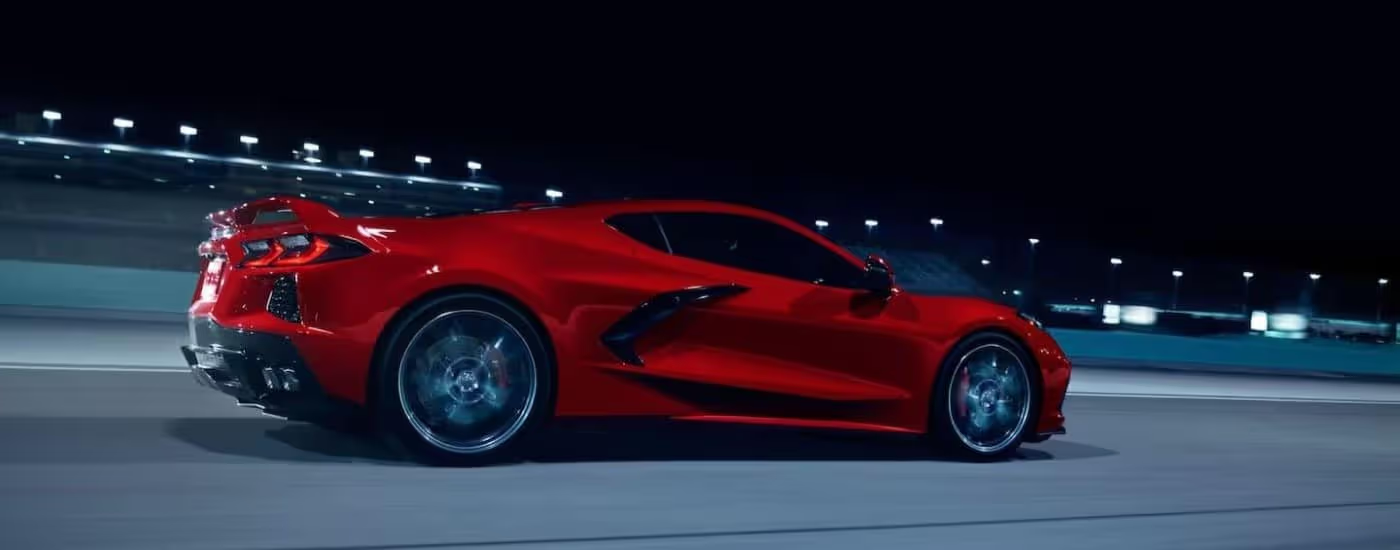 Red 2024 Corvette Stingray driving on a floodlit racetrack at night